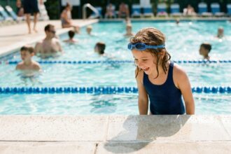 Jeune fille en maillot de bain au bord d'une piscine municipale en été, prête à plonger