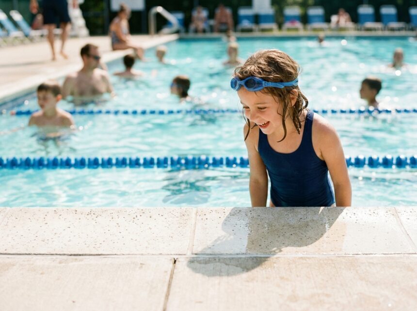 Jeune fille en maillot de bain au bord d'une piscine municipale en été, prête à plonger