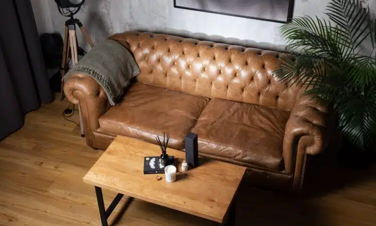 a brown leather couch sitting on top of a wooden table