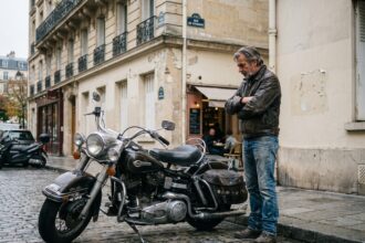 Harley-Davidson garée dans une rue pavée urbaine à Paris avec son propriétaire, illustrant le stationnement en ville pour l'assurance moto