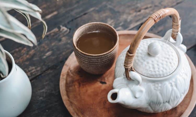 white and brown ceramic teapot on wooden tray