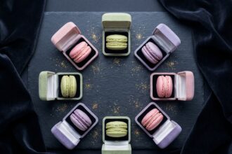 Macarons colorés présentés dans des écrins à bijoux sur fond d'ardoise noire, mise en scène élégante vue du dessus